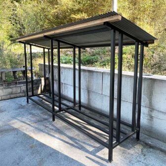 黒いスチール製フレームと屋根が付いた2ブロック構造の屋外用薪棚